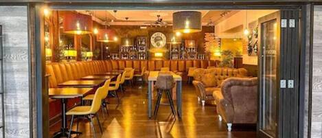 A bar and grill with leather booths, wooden tables, and a warm interior.