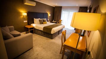A hotel room with a bed, a sofa, a desk, and a chair.