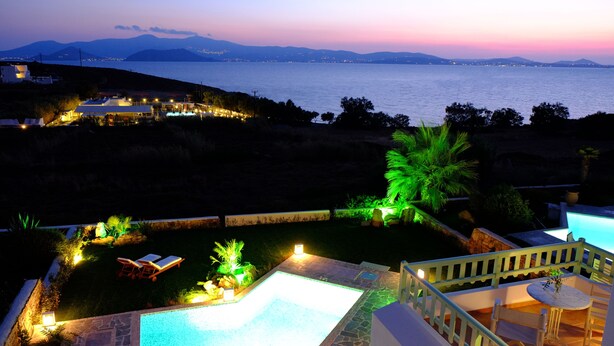 A pool area with a view of the sea and mountains at dusk. - Valea Villa (Naxos)