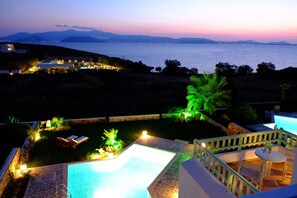 A pool area with a view of the sea and mountains at dusk. - Valea Villa (Naxos)