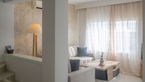 A modern hotel room with a sofa, a coffee table, and a lamp. - Valea Villa (Naxos)