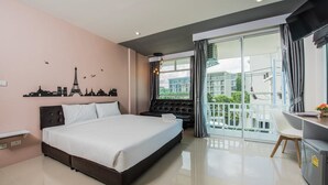 A modern hotel room with a large bed, a desk, and a balcony with a view of the city. - Slowlife Beach - Hostel (Sa Khu)
