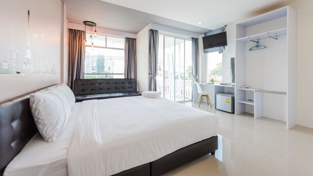 A modern hotel room with a large bed, a desk, a wardrobe, and a balcony with a city view. - Slowlife Beach - Hostel (Sa Khu)