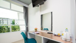 A modern hotel room with a large window, a desk with a chair, a small kitchenette, and a flat-screen TV mounted on the wall. - Slowlife Beach - Hostel (Sa Khu)