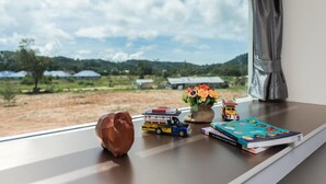 A window view of a rural landscape with a clear sky, a small table with a toy truck, a book, and a flower vase. - Slowlife Beach - Hostel (Sa Khu)