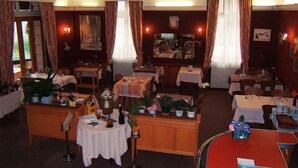 Un comedor con varias mesas dispuestas para comidas, rodeado de sillas.