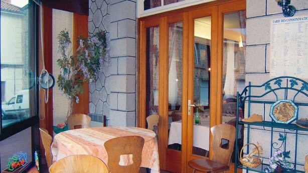 Un comedor con una mesa, sillas, una planta en maceta y una estantería con objetos.