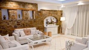 Una sala de estar con mobiliario blanco, una pared de piedra y un espejo decorativo.