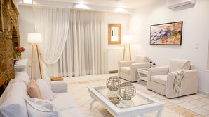 Una sala moderna con un sofá blanco, una mesa de centro de vidrio y dos lámparas de pie.