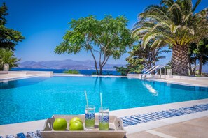 A swimming pool with a clear view of mountains and the sea in the background. - Montana Villa (Naxos)