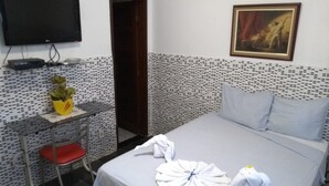 Una habitación de hotel con cama, escritorio, silla, televisor y un cuadro en la pared.