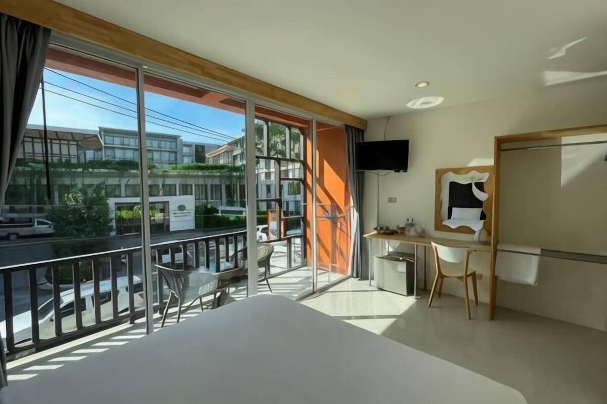Habitación de hotel con balcón, cama, escritorio y televisión.