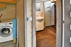 A compact bathroom with a washing machine, sink, and shower.
