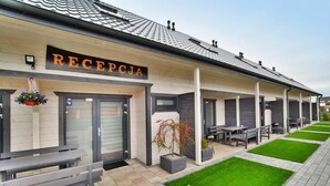Een gebouw met een receptie, terras en een verzorgd gazon.