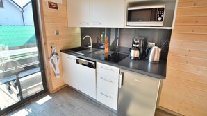 Een moderne keuken met witte kasten, een RVS vaatwasser, een magnetron en een koffiezetapparaat.