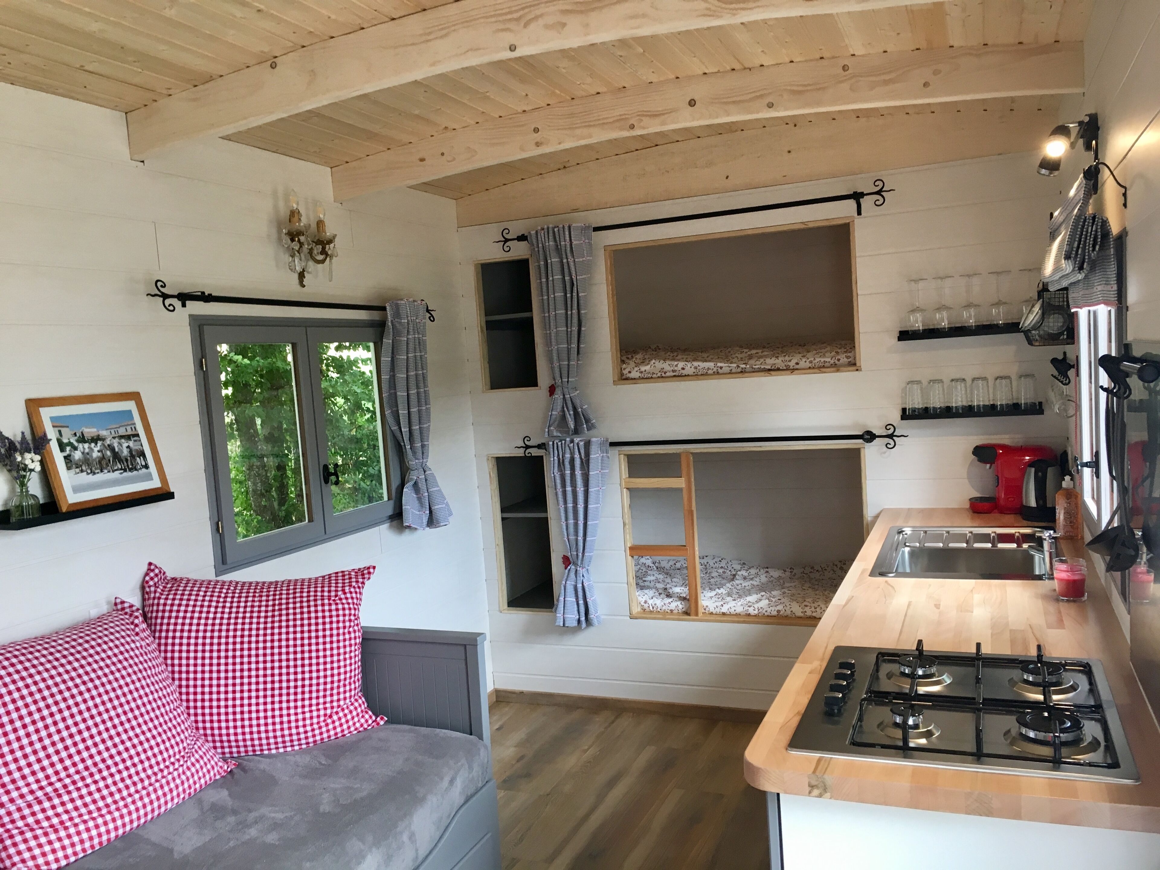 Une cuisine de taille réduite, équipée d’une cuisinière à gaz, d’un évier et d’une fenêtre avec des rideaux.