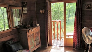 A cozy cabin with a wooden interior, a large window, a wooden bench outside, and a fan on the right. - Le Mas Du Fort  (Gargas)