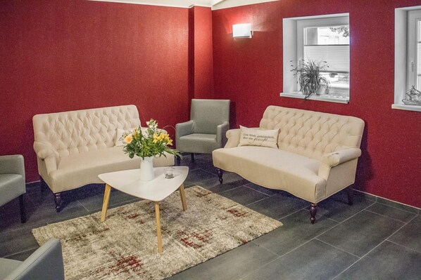 Una sala de estar con dos sofás color crema, una mesa de centro blanca y un sillón gris.
