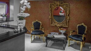 Une pièce comprenant deux fauteuils richement décorés, une petite table, un miroir et une plante en pot.