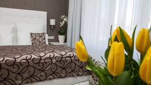 Une chambre d’hôtel avec un lit, une table de chevet, une lampe et une plante en pot.