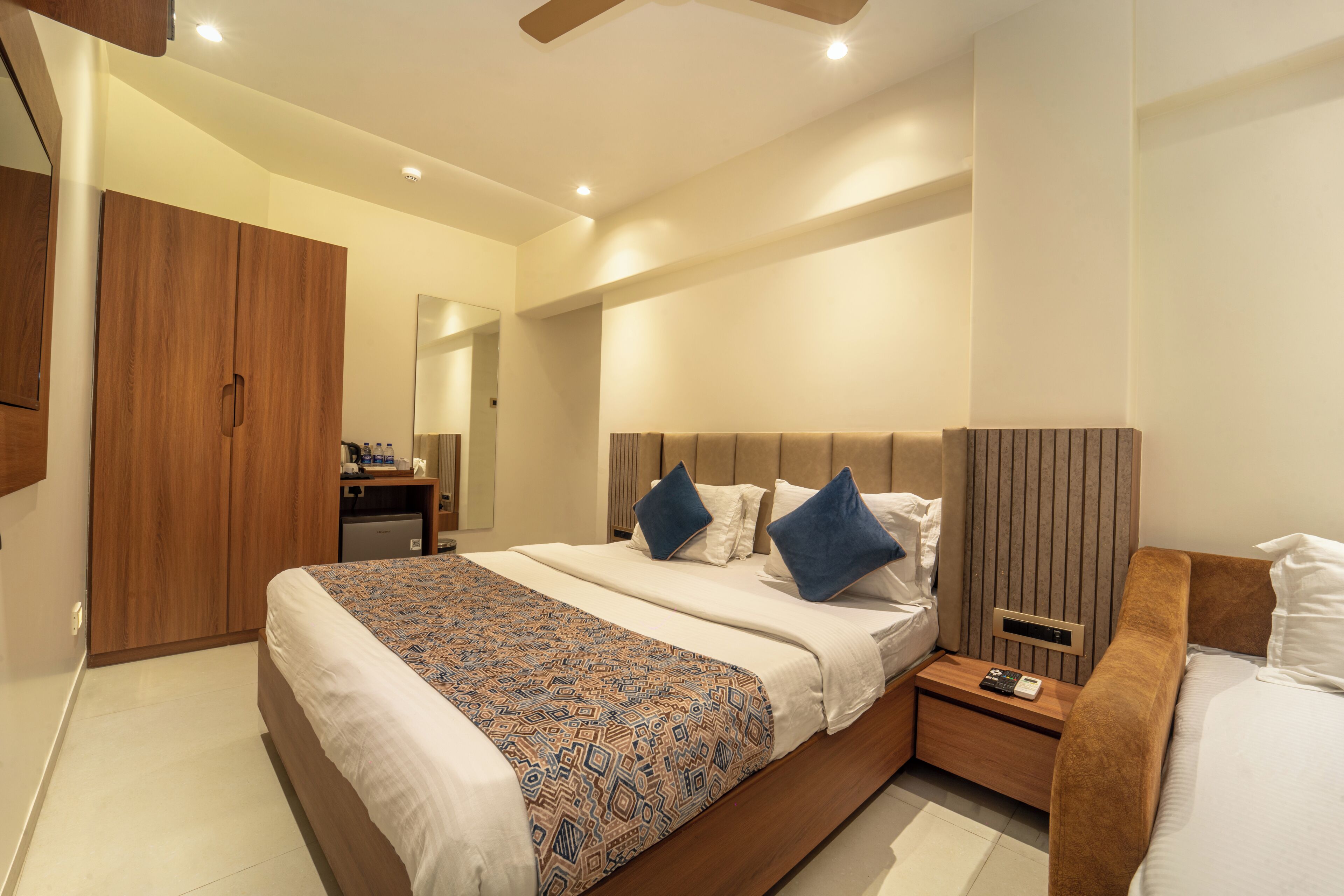 A modern bedroom with a large bed, bedside tables, a wardrobe, and a mirror.