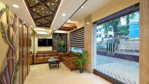 A modern lobby with leather sofas, a coffee table, and a potted plant. - Hotel Kalpana Palace (Mumbai)