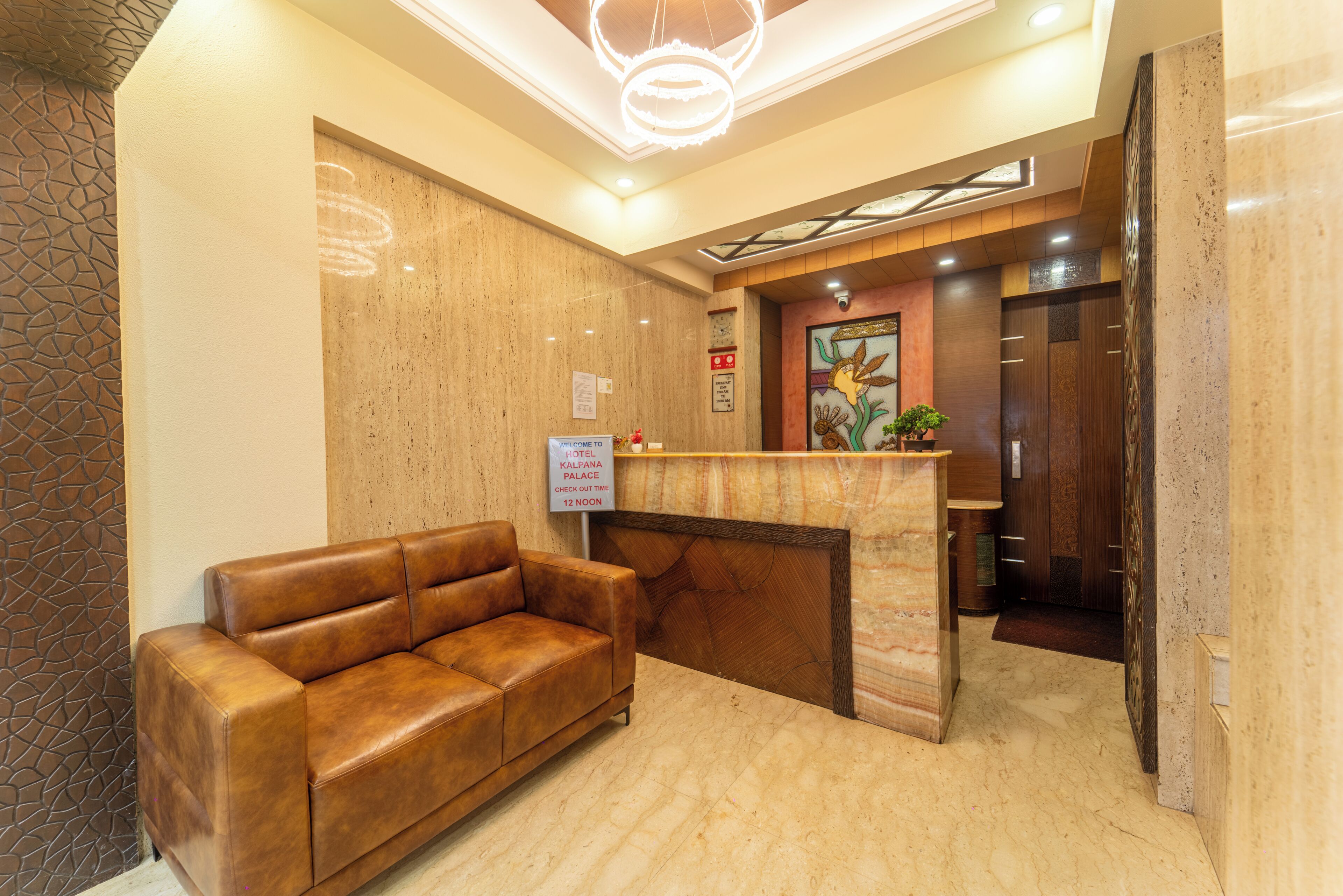 A hotel reception area with a leather sofa, a reception desk, and a sign indicating the hotel name and address.