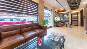 A modern lobby with a leather sofa, a glass coffee table, and a large window with blinds. - Hotel Kalpana Palace (Mumbai)