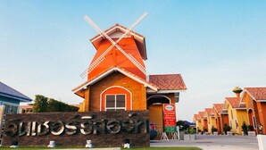 A building with a windmill, a sign reading "Olives & Olives," and a row of similar buildings with orange roofs. - Windsor Park and Resort (Lop Buri)