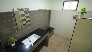 A modern bathroom with a black sink, a mirror, and a potted plant. - Windsor Park and Resort (Lop Buri)