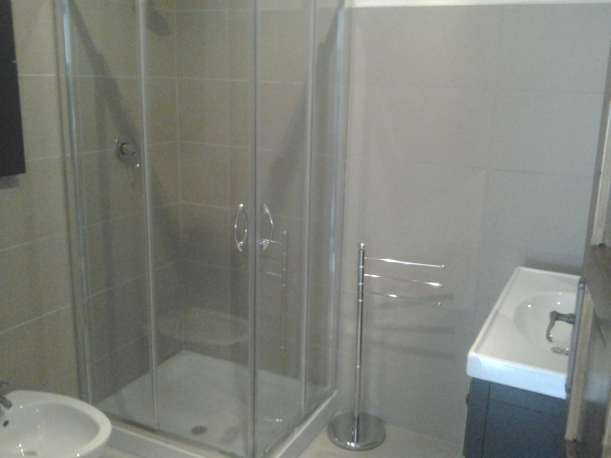 Une salle de bain avec une douche à parois de verre, un lavabo et des toilettes.