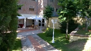 A courtyard with a covered seating area, outdoor furniture, and a pathway leading to a building entrance. - Villa Cardinal Apartments (Tivoli)