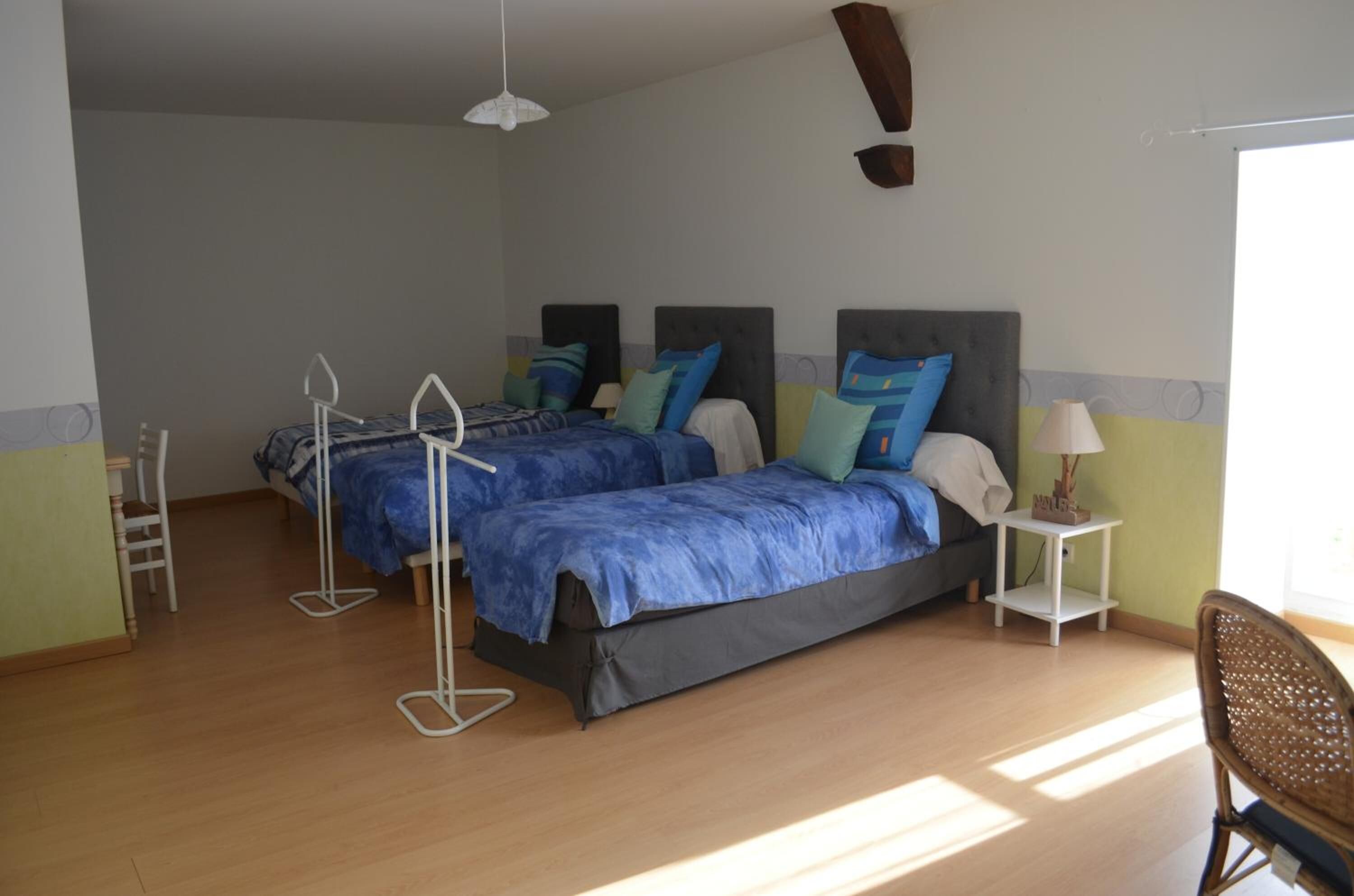 Un dormitorio con dos camas, una silla, una mesita y una lámpara colgante.