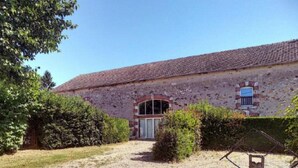 A rustic stone building with a tiled roof, a central entrance with a glass door, and a gravel driveway. - Logis De Chezelles (Sidiailles)