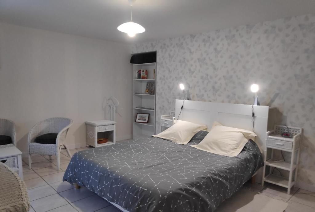 A bedroom with a bed, two bedside tables, a chair, a wardrobe, and a shelf with books.