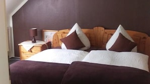 Un dormitorio con techo inclinado, estructura de cama de madera y mesita de noche con lámpara.