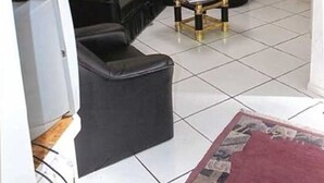 Una sala de estar con un sofá de cuero negro, una pequeña mesa de centro y un televisor.