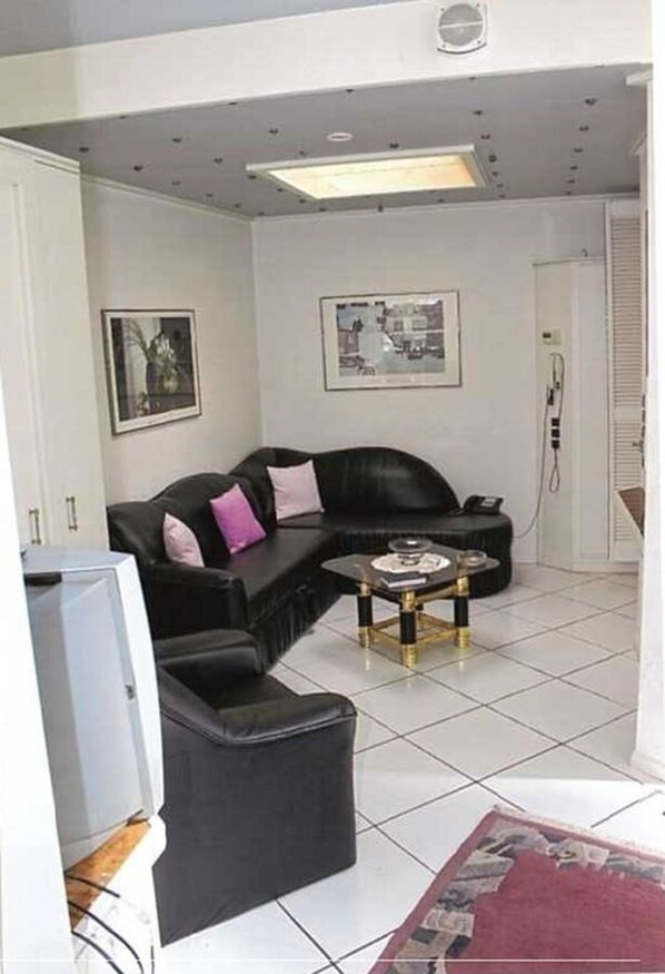 A living room with a black leather sofa, a small coffee table, and a television.