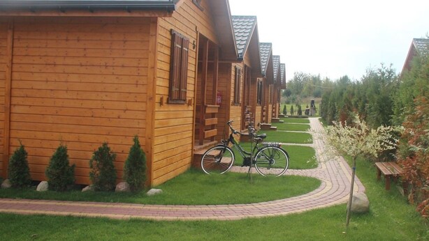 A row of wooden cabins with a paved pathway leading to them. - Nemo Domki Letniskowe (gmina Wolin)