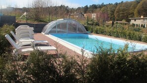 A swimming pool with a glass enclosure, surrounded by lounge chairs and greenery. - Nemo Domki Letniskowe (gmina Wolin)