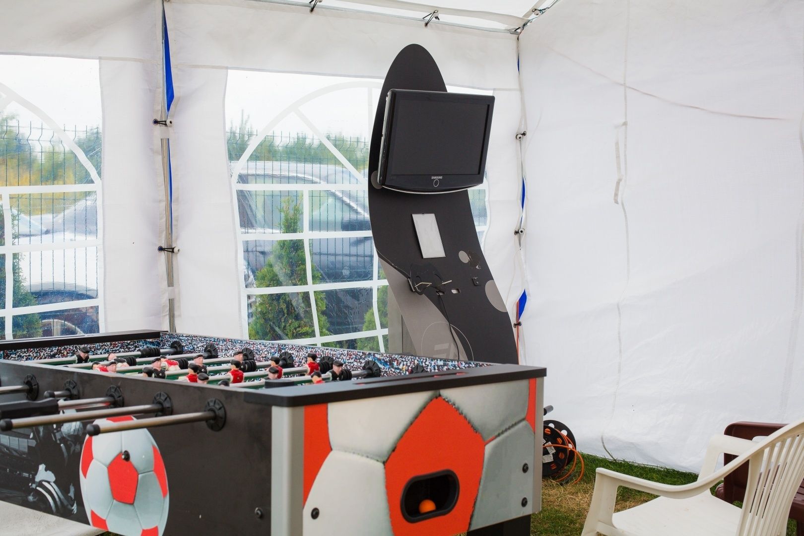 A foosball table in a tent with a Samsung TV mounted on the wall.