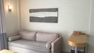 A living room with a sofa, a small wooden table, a lamp, and a wall-mounted artwork.