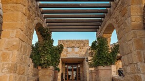 A stone building with a reception area, wooden pergola, and potted plants. - Old Village Resort (Wadi Musa)