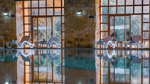 A pool area with lounge chairs and a stone wall. - Old Village Resort (Wadi Musa)