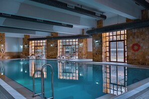 An indoor swimming pool with clear water, stone walls, and a lifebuoy on the right.