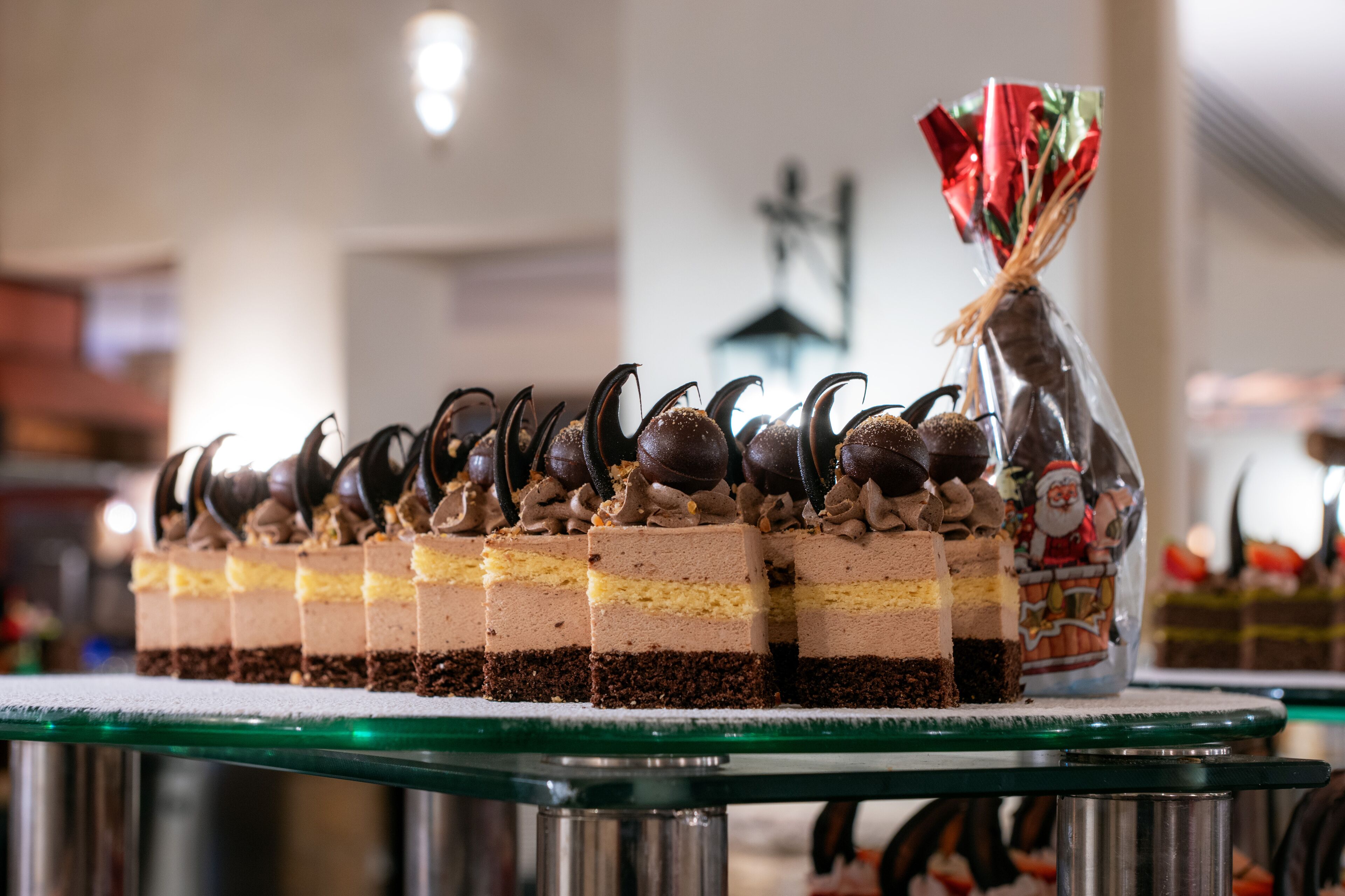 Een dessertpresentatie met laagjes taart en chocolade decoraties op een glazen tafel.