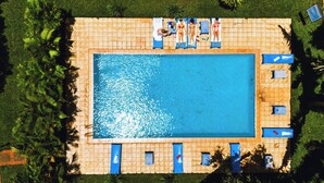 An aerial view of a rectangular swimming pool surrounded by a tiled deck, with lounge chairs and a few people. - Keys Hotel (Moshi)