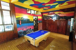A pool table in a room with wooden walls and a mural depicting a sunset and a mountain scene.
