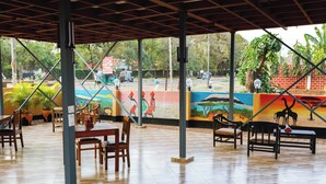 An indoor dining area with wooden tables and chairs, large windows, and a mural on the wall. - Keys Hotel (Moshi)