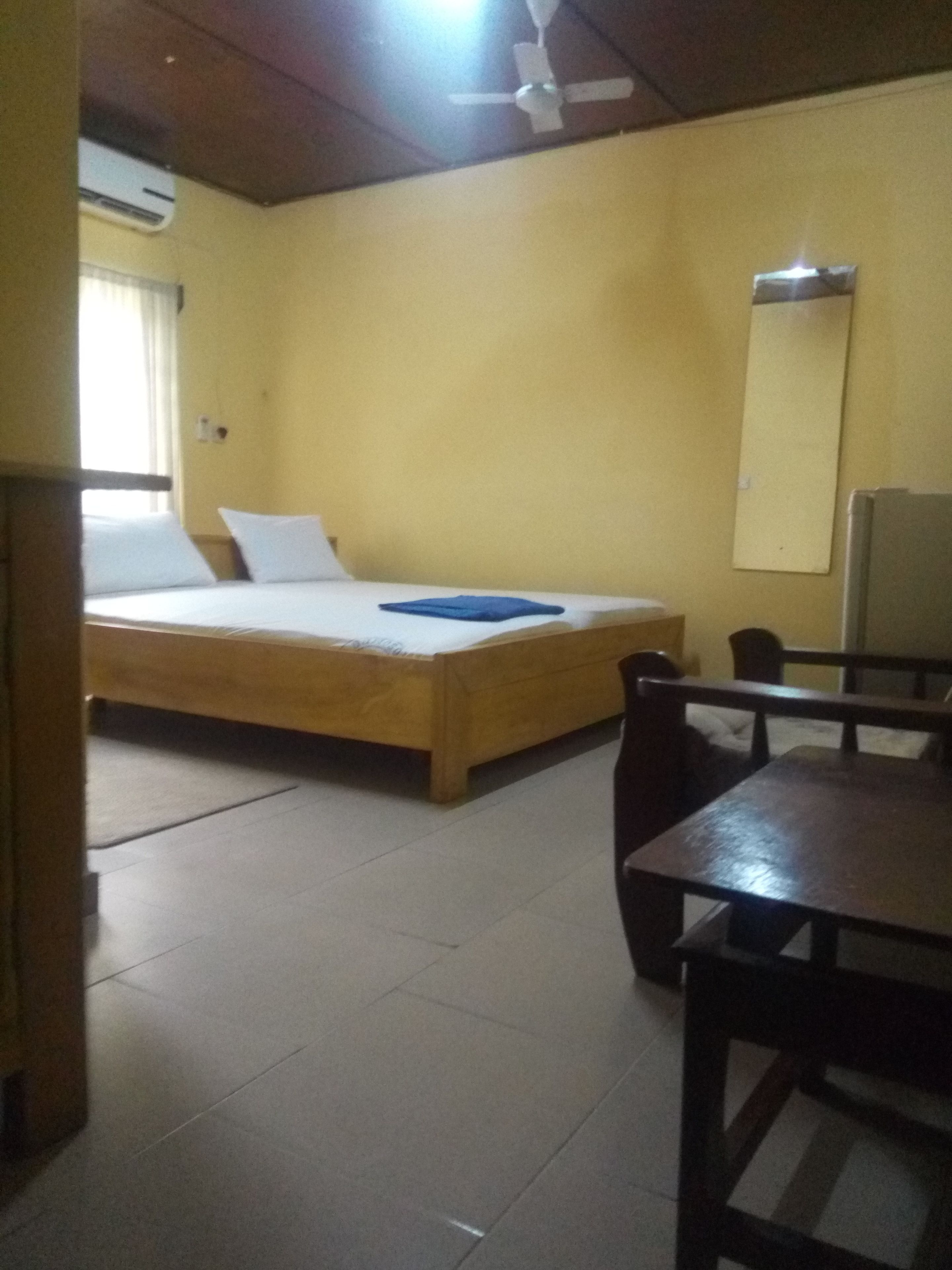 Una habitación con cama, una mesa y un ventilador de techo.